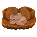 A collection of raw Madagascar rose quartz crystals displayed in a wooden bowl.